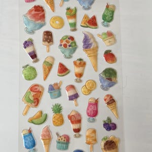 May include: A sheet of colourful stickers featuring various ice cream treats. Designs include ice cream cones, ice lollies, sundaes, and fruit slices. The stickers are in a variety of colours, including pink, blue, green, and yellow. Ideal for scrapbooking or decorating.