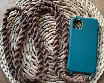 May include: A brown braided phone strap with a dark green phone case on a woven straw background.
