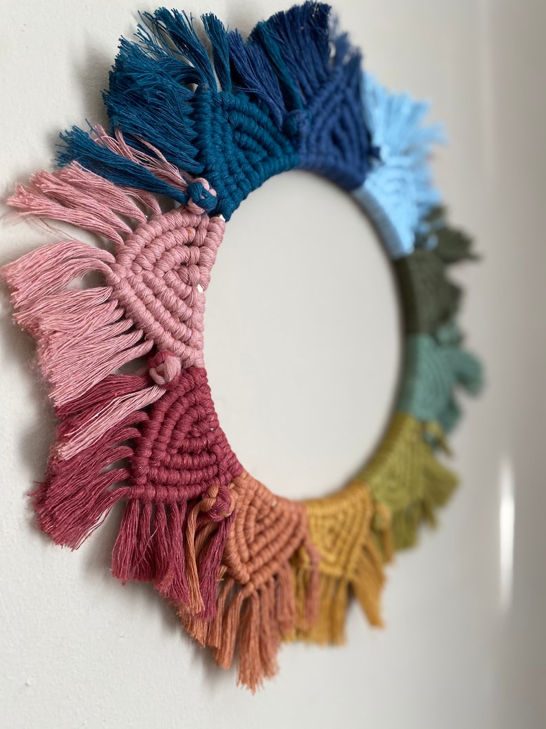 Puede incluir: Un tapiz de macram&eacute; de pared colorido con forma circular y detalles de flecos. El tapiz presenta un arco&iacute;ris de colores, incluyendo rosa, rojo, naranja, amarillo, verde, azul y turquesa.