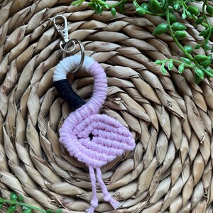 May include: Pink and black yarn flamingo keychain with a silver key ring.
