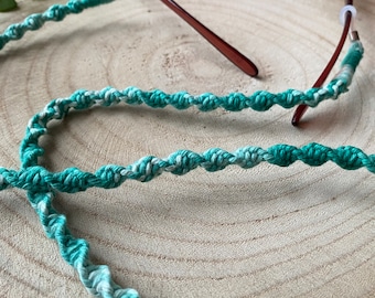 May include: A green and white braided cord with plastic ends for holding sunglasses. The cord is twisted and has a gradient color effect.