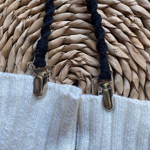 May include: Two white socks with black elastic straps and silver clips. The straps are twisted and the clips are attached to the socks.