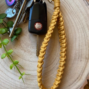 May include: A mustard yellow braided key chain with a silver key ring and a car key attached.
