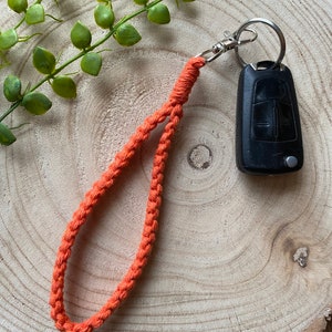 May include: A bright orange braided key chain with a silver key ring and a black car key.