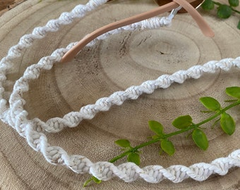 May include: White and gold braided glasses chain with a twisted design. The chain is looped around a pair of pink sunglasses.