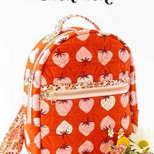 May include: A quilted orange backpack with a strawberry pattern and a floral zipper. The text "THE VIOLET BACKPACK" is at the top. The backpack has a top handle and a floral strap. The brand logo "KNOT + THREAD design" is at the bottom.