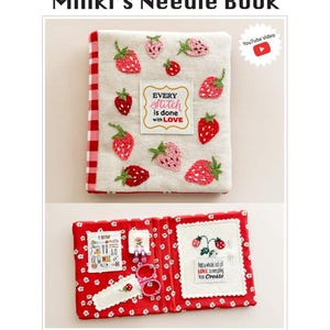 May include: A handmade needle book titled "Minki's Needle Book" with embroidered strawberries on a cream-colored cover. The book has a red and white gingham spine and opens to reveal a red interior with floral patterns and embroidered details. The text "Every stitch is done with LOVE" is visible.