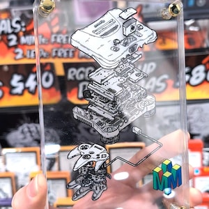 May include: A clear acrylic display showing a detailed exploded diagram of a Nintendo 64 console and controller. The artwork includes the console's internal components and the "N64" logo in green, blue, and yellow. Gold screws secure the acrylic.