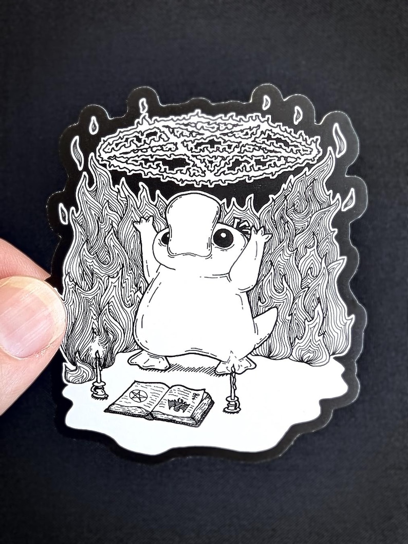 May include: A black and white illustration of a platypus performing a ritual. The platypus is standing on a book with a pentagram symbol. There are candles on either side of the book. The platypus is surrounded by flames and a pentagram symbol is above its head.