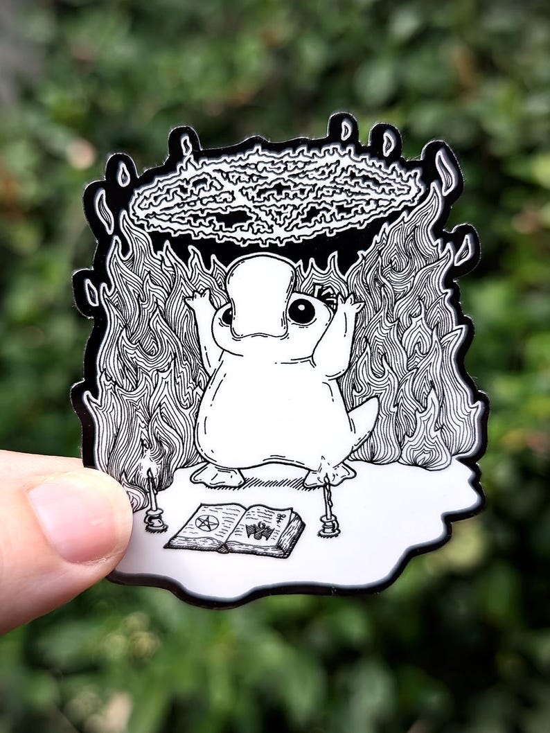 May include: Black and white illustration of a cartoon frog holding a pentagram above its head. The frog is standing on a book with a pentagram on the cover. There are candles on either side of the book.