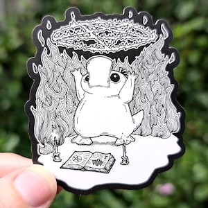 May include: A black and white illustration of a platypus performing a magic trick. The platypus is standing on a book with a pentagram symbol and surrounded by flames. Above the platypus is a swirling cloud of smoke.