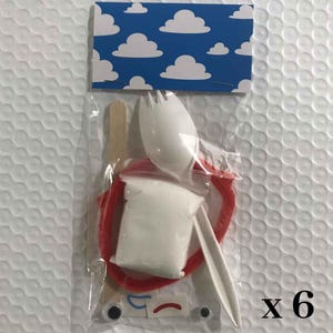 May include: A craft kit in a clear plastic bag with a blue and white cloud-patterned header. The kit contains a white plastic spork, a small bag of white powder, a red pipe cleaner, a wooden stick, two googly eyes, and small sticker decals.