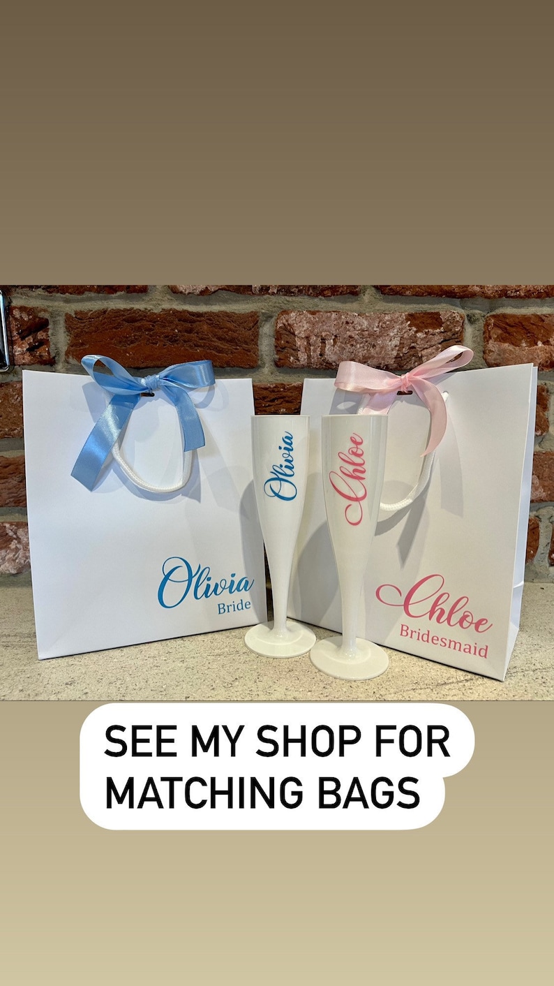 May include: Two white gift bags with blue and pink ribbons. The bags are decorated with the names "Olivia Bride" and "Chloe Bridesmaid".