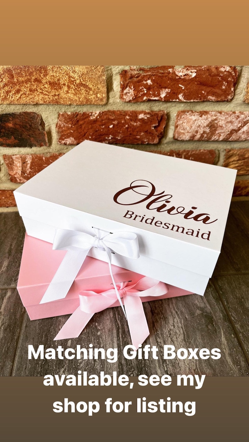 May include: Two white gift boxes with pink ribbon bows. The top box has the name "Olivia Bridesmaid" printed on it in brown lettering.