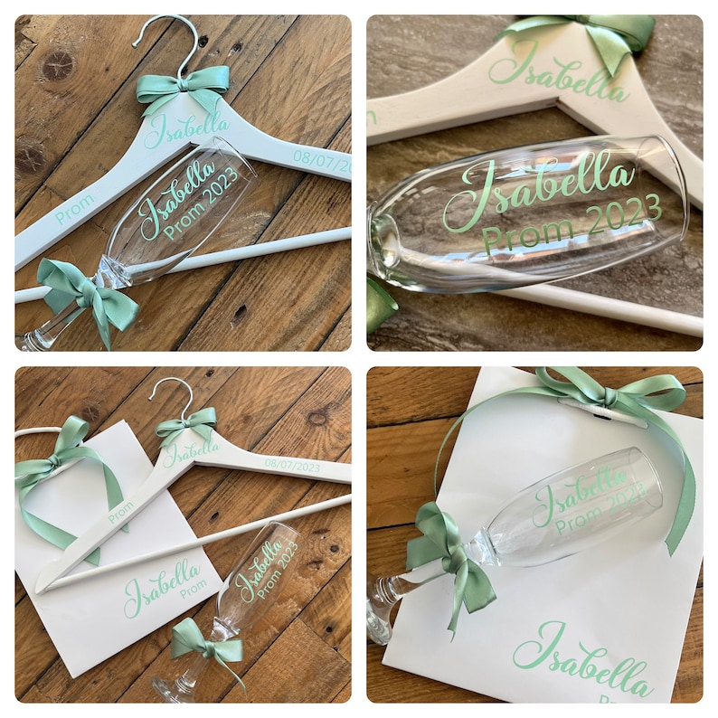 May include: A set of personalized prom decorations featuring a white wooden hanger, a champagne flute, and a white gift bag. All items are decorated with the name "Isabella" and the date "Prom 2023" in a light green font.