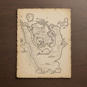 May include: A rectangular map of Morrowind printed on aged, textured parchment paper with deckled edges. The map features black ink illustrations of landmasses, mountain ranges, and bodies of water, with labels including Vvardenfell, Balmora, and Vivec.