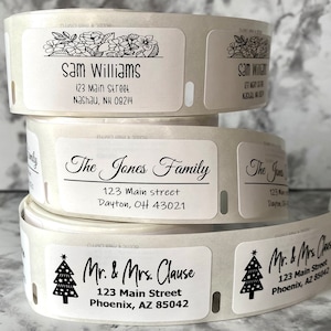 May include: Rolls of address labels with various names and addresses printed in black ink. One label features the name "Sam Williams" and address. Another label reads "The Jones Family". A third label reads "Mr. & Mrs. Clause".