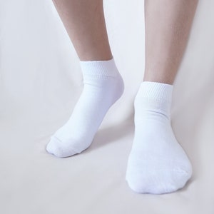 May include: A pair of white ankle socks on a person's feet. The socks are made of a soft, comfortable material and are perfect for everyday wear.