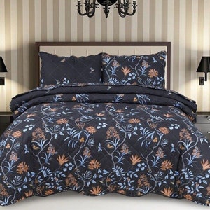 May include: A black and blue floral patterned quilt with a quilted design. The quilt is on a bed with two matching pillowcases.
