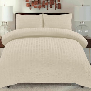 May include: A cream-coloured duvet cover with a subtle ribbed texture. The duvet cover is on a bed with two matching pillowcases.