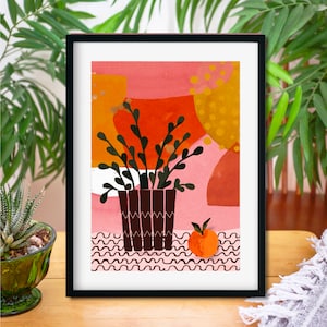 May include: A framed print with an abstract design featuring a potted plant with green leaves and a single orange fruit on a pink and orange background.