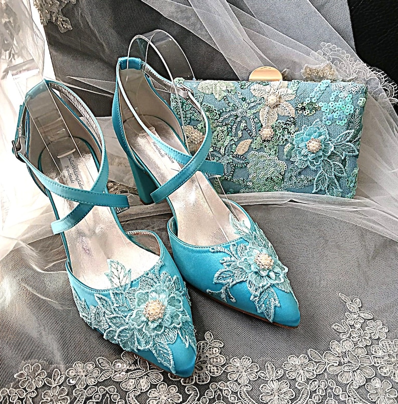 Pode incluir: Um conjunto de sapatos de noiva turquesa e uma clutch. Os sapatos t&ecirc;m bico fino, tiras no tornozelo e detalhes de renda floral. A clutch &eacute; retangular, com fecho dourado e adornada com lantejoulas e bordados florais.