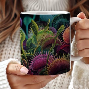 May include: White ceramic mug featuring a colorful illustration of Venus flytraps. The design showcases detailed depictions of the carnivorous plants in shades of green, purple, and red against a dark background. The mug has a standard handle.