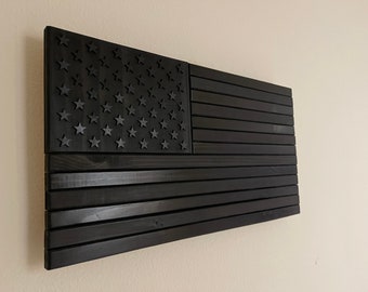 Puede incluir: Una bandera americana de madera negra con un diseño en relieve de estrellas y rayas.