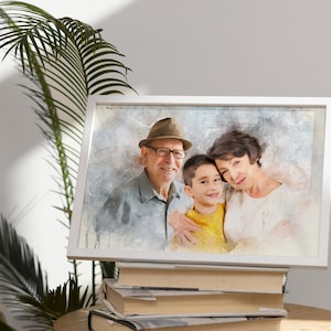 May include: A watercolor painting of a family, a man wearing a hat and glasses, a woman, and a young boy. The family is smiling and appears to be close. The painting is framed in a white frame and is sitting on a stack of books.