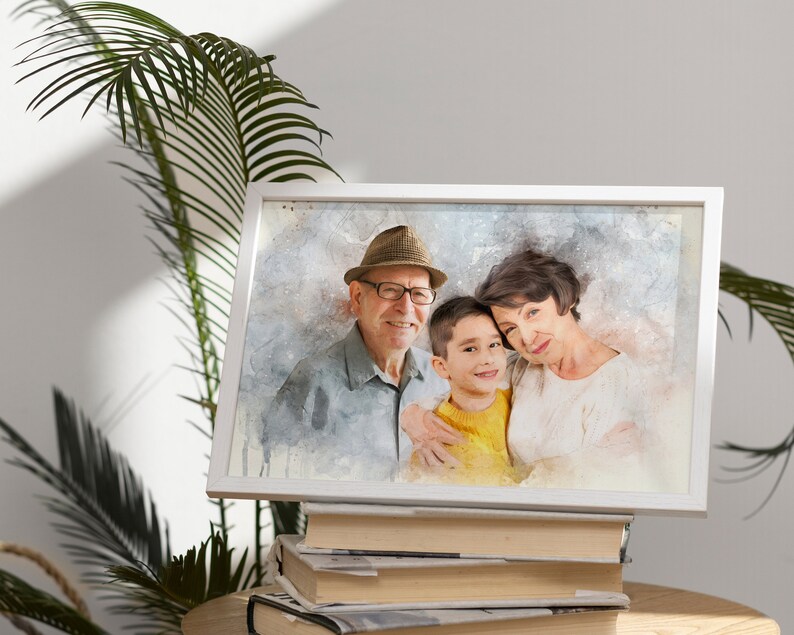 May include: A watercolor painting of a family, a man wearing a hat and glasses, a woman, and a young boy. The family is smiling and appears to be close. The painting is framed in a white frame and is sitting on a stack of books.