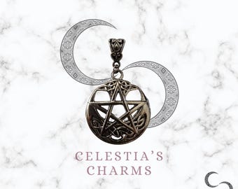 May include: Silver pendant charm featuring a pentacle with a Celtic knot design. The charm is hanging from a silver bail. The background is a white marble surface with a crescent moon design.