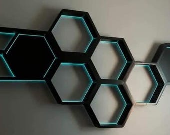 May include: A wall-mounted shelf unit made of black wood, shaped like a honeycomb. The shelves are illuminated with blue LED lights.
