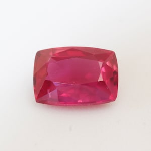 May include: A deep pink gemstone with a rectangular cushion cut.