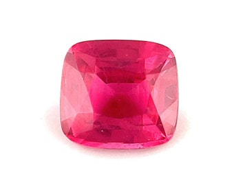 May include: A vibrant, deep red gemstone with a cushion cut. The gemstone is faceted and has a high polish.