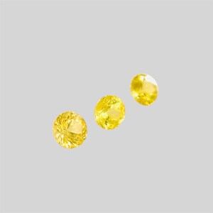 May include: Three yellow gemstones, each with a different size and cut, are displayed on a white background.