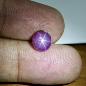 May include: A purple star sapphire gemstone with a six-pointed star in the center.