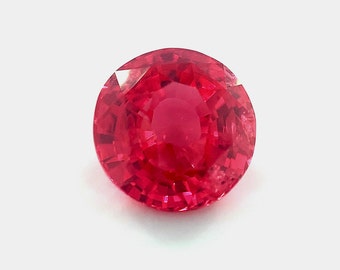 May include: A round, faceted, red gemstone with a high polish.