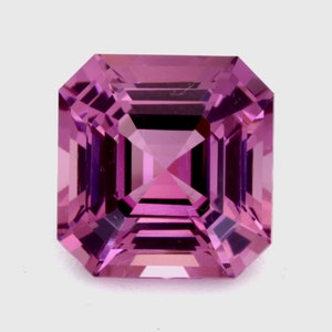 May include: A square-shaped, faceted gemstone with a purple hue. The gemstone is cut in a step-cut style, creating a series of flat facets that reflect light.
