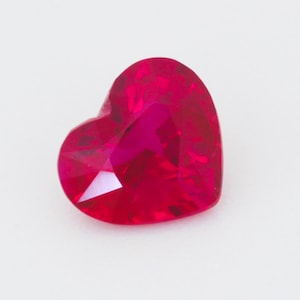 May include: A heart-shaped ruby gemstone with a deep red colour.