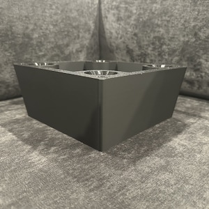 May include: Black square-shaped furniture leg with four rounded holes on the top.