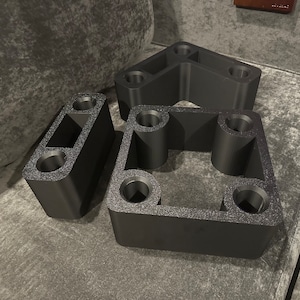 May include: Three black plastic spacers with different shapes and sizes. The spacers have multiple holes on each side.