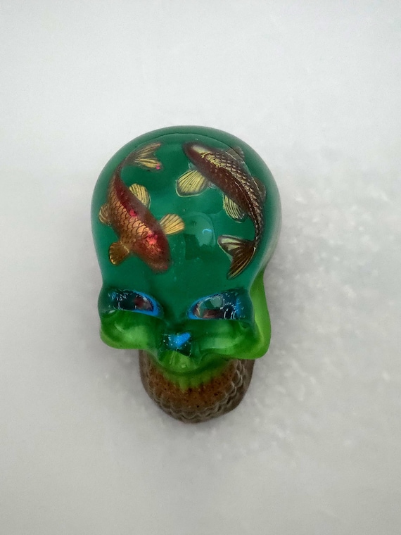 A chunky hand-cast resin skull with koi fish suspended inside — the juxtaposition of gothic and serene Japanese aesthetic makes this a genuinely striking desk object that sparks conversation.