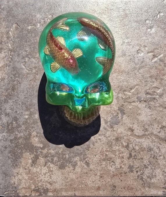 A chunky hand-cast resin skull with koi fish suspended inside — the juxtaposition of gothic and serene Japanese aesthetic makes this a genuinely striking desk object that sparks conversation.