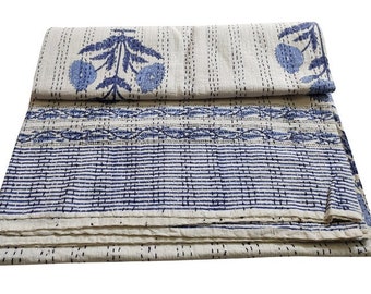 May include: A white and blue kantha quilt with a floral pattern. The quilt is folded in thirds and has a fringed edge.