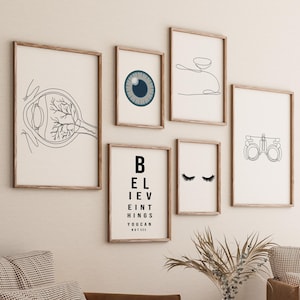 May include: A gallery wall of six black and white line drawings with an eye chart in the center. The drawings include an eye, eyelashes, glasses, and a stylized eye.