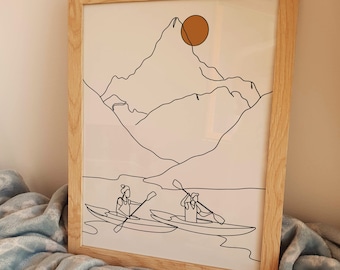 May include: A framed line art print of two people kayaking in front of a mountain range with a large orange sun in the sky.