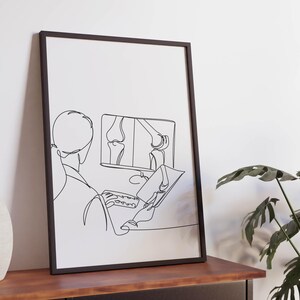 May include: Black and white line art print of a doctor looking at an x-ray of a knee on a computer screen. The print is framed in a black frame and is hanging on a wall.