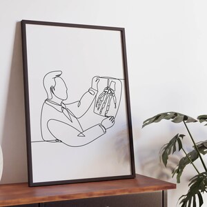 May include: Black and white line art print of a person looking at an x-ray image. The print is framed in a black frame and is hanging on a white wall.