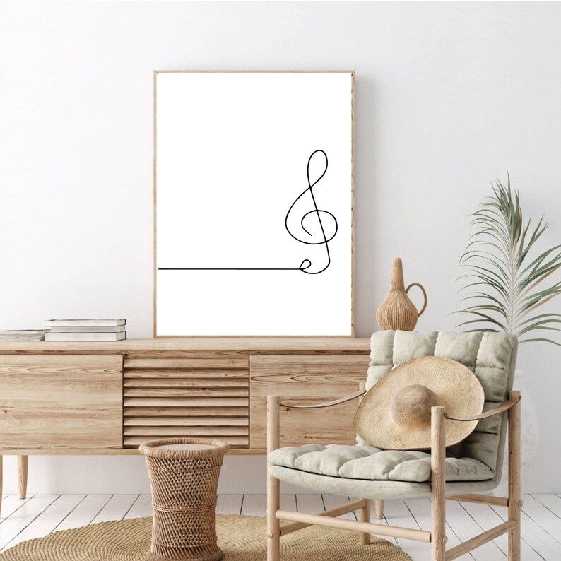 May include: A black and white line drawing of a treble clef on a white background. The drawing is framed and hanging on a white wall.