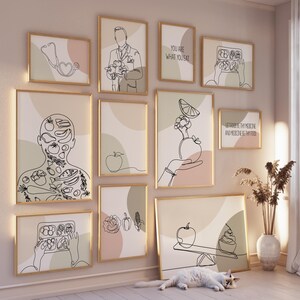 Op de afbeelding: Een verzameling ingelijste kunstdrukken met lijntekeningen over thema's als voeding en gezondheid. De prints tonen afbeeldingen van een stethoscoop, een dokter en diverse groenten en fruit. Sommige prints bevatten tekst: "You are what you eat" en "Let food be thy medicine and medicine be thy food."